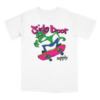 A white short-sleeve crewneck t-shirt featuring a colorful graphic of a green cartoon character riding a pink skateboard, with the text 'Side Door supply' in pink and black.
